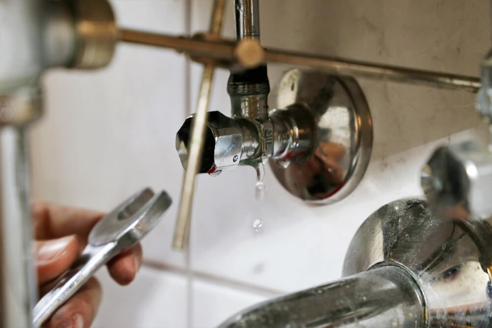 Someone checking for leaks under a bathroom basin sink.