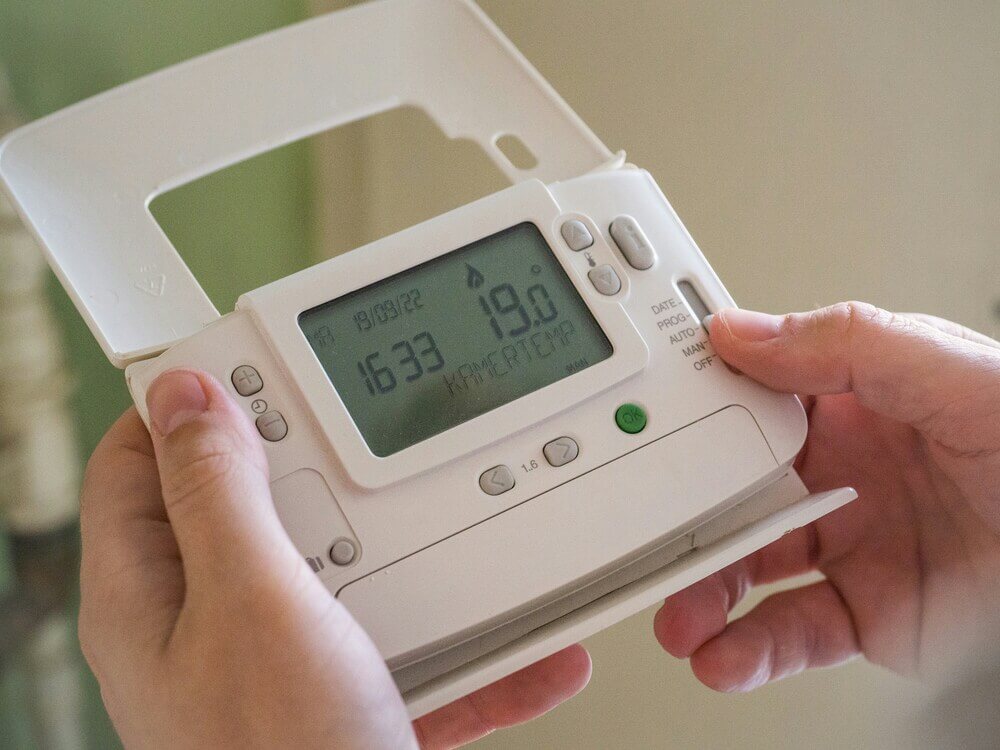 Set up or upgrade heating controls. Someone holding a heating control.