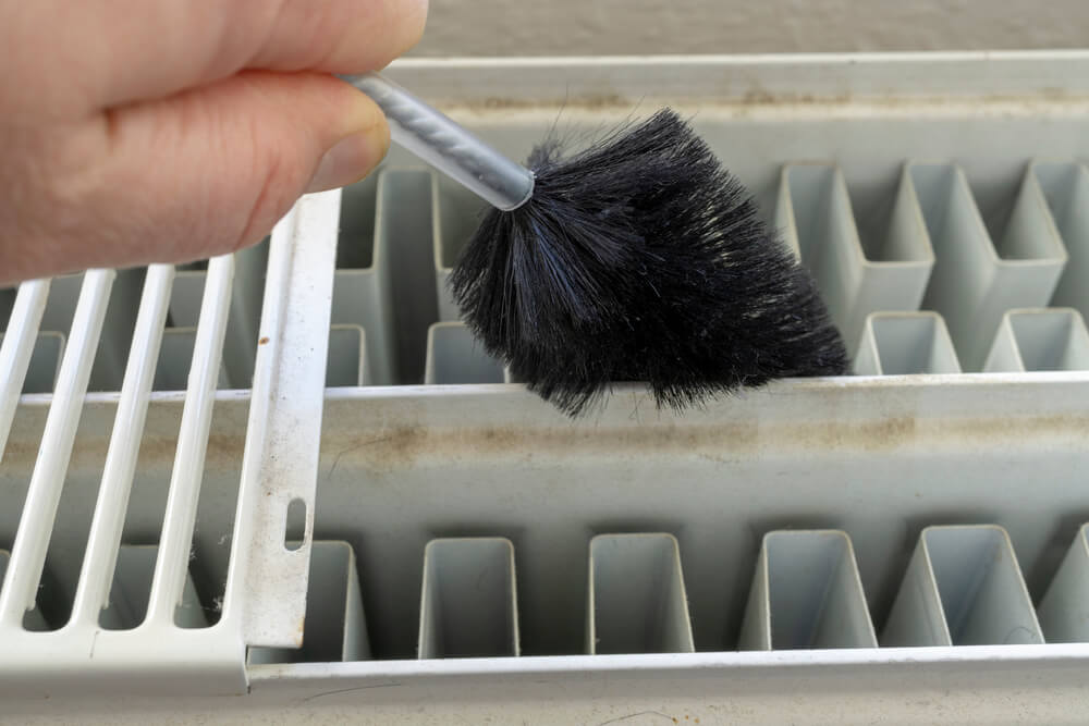 Close up of someone cleaning radiator with top grill